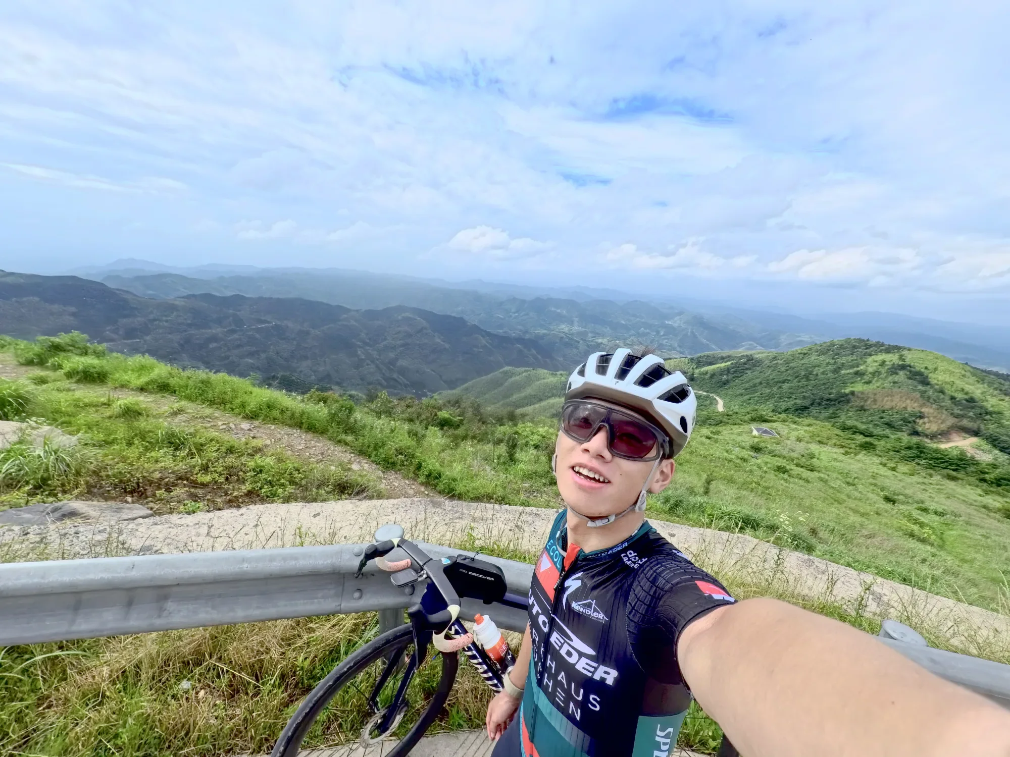 骑行者在山顶公路旁与连绵群山自拍